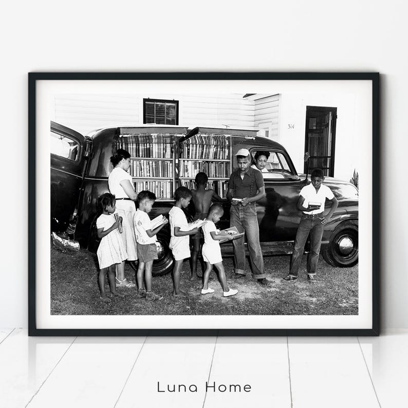 African-American children secure books at a North Carolina Albemarle Region bookmobile stop. Black woman is in the front seat of the bookmobile (1950).