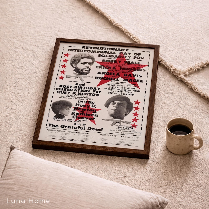 Pu&ograve; includere: Un poster incorniciato con una cornice in legno marrone, con testo e immagini relative a un evento politico. Il poster include il testo "Revolutionary Intercommunal Day of Solidarity" e i nomi Bobby Seale, Ericka Huggins, Angela Davis e Ruchell Magee.