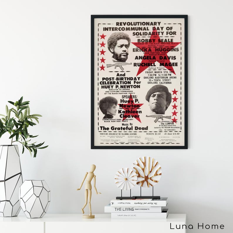 Pu&ograve; includere: Un poster incorniciato con bordo nero presenta testo e ritratti di personaggi politici. Il testo del poster include "Revolutionary Intercommunal Day of Solidarity" e "Huey P. Newton". Il poster ha un'estetica vintage con stelle rosse e sfondo crema.