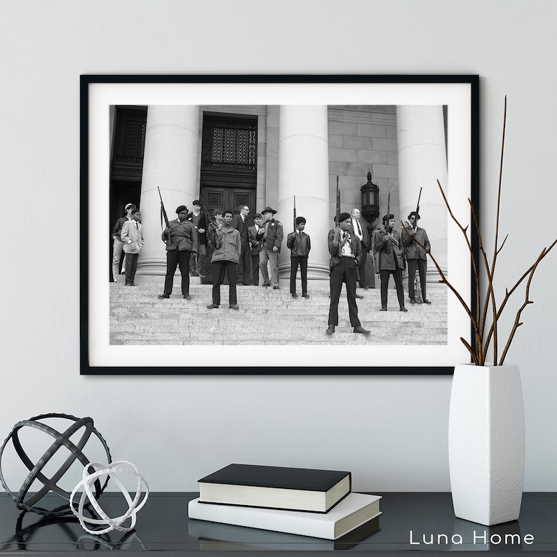 May include: Black and white framed print of a group of people standing on steps in front of a building. Several people are holding rifles. The image is a historical photograph.