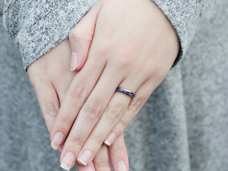 May include: A thin silver band ring with a purple glitter inlay.