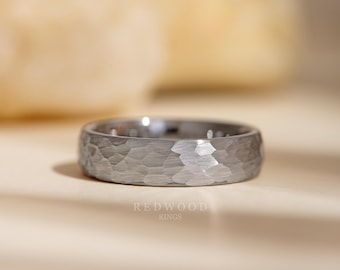 May include: A textured, silver-colored ring with a hammered finish. The ring has a band with a series of small holes. The brand name "REDWOOD RINGS" is printed in white at the bottom of the image.