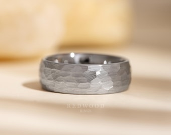 May include: A close-up of a silver ring with a hammered texture. The ring is wide and has a rounded shape. The text "REDWOOD RINGS" is visible at the bottom of the image.