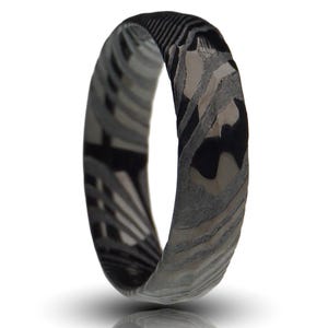 May include: A ring with a unique pattern of black, gray, and white swirls. The ring's design features a marbled effect, with the colors blending together to create a distinctive look. The ring is a band style, with a smooth, polished finish.