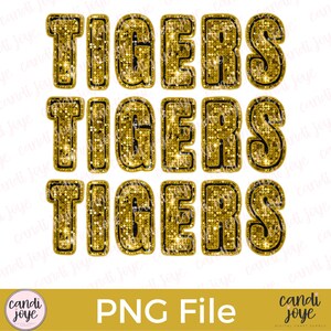 May include: Three sets of gold glitter letters spelling out the word "TIGERS". The letters have a black outline and are set against a white background.
