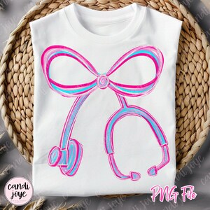 May include: White t-shirt featuring a pink and blue stethoscope design. The stethoscope is stylized with a bow at the top and the text "PNG File" at the bottom right. The design is in a watercolor style.