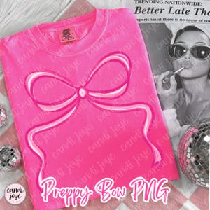 May include: A vibrant pink t-shirt featuring a large bow design in pink and white. The text "Preppy Bow PNG" is at the bottom. The shirt is a Comfort Colors brand. A black and white image of a woman is in the background.