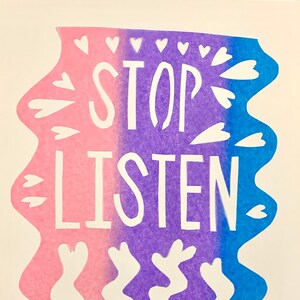 May include: A white paper print with a pink, purple, and blue ombre background. The print features the words "STOP LISTEN" in white, surrounded by white hearts.