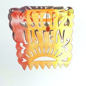 May include: A yellow, orange and red paper cutout with the words "STOP & LISTEN" in black lettering. The cutout has a sun design at the bottom and a scalloped edge.