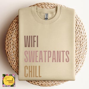May include: A beige sweatshirt with the text "WIFI SWEATPANTS CHILL" printed in pink and brown.