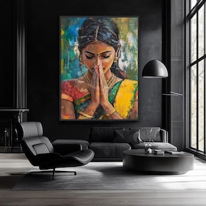 Indian wall art May include: An oil painting depicts a woman in traditional Indian attire with hands clasped in prayer. The artwork features vibrant colors, including red, yellow, and green, set against a backdrop of blue and teal. Gold jewelry adorns the woman.