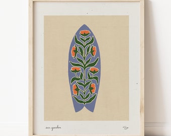 Puede incluir: Una impresión enmarcada de una tabla de surf azul con un diseño floral estilizado en tonos de verde, naranja y blanco. El texto "sea garden" está impreso debajo de la imagen.