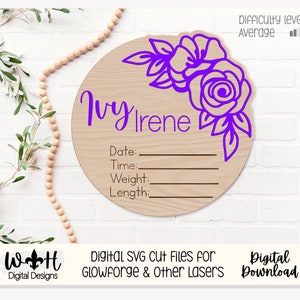 Könnte beinhalten: Ein rundes Holzschild mit einem violetten Blumenmuster und dem Text "Ivy Irene" mit Platz für Datum, Uhrzeit, Gewicht und Länge. Das Schild ist perfekt für eine Babyparty oder ein Kinderzimmer.
