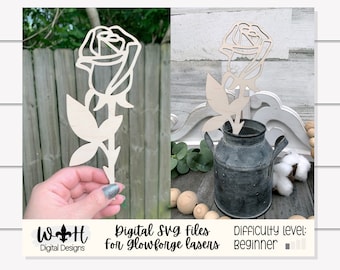 Könnte beinhalten: Ein Holzausschnitt einer Rose mit einem einzelnen Stiel und Blatt. Die Rose steht in einer rustikalen Metallvase. Der Text "Digital SVG files for Glowforge lasers" und "Difficulty level: beginner" ist unter dem Bild sichtbar.