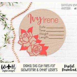 Könnte beinhalten: Runder Holzschild mit dem Namen "Ivy Irene" in korallfarbener Schrift. Es gibt Platz für Datum, Uhrzeit, Gewicht und Länge, mit Illustrationen von korallenfarbenen Rosen. Der Schwierigkeitsgrad ist "Mittel".