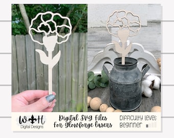 Könnte beinhalten: Ein Holzausschnitt einer Nelke mit Stiel und Blättern. Die Blume wird in zwei verschiedenen Positionen gezeigt, einmal in einer Hand und einmal in einer Metallmilchkanne. Der Text "Digital SVG files for Glowforge lasers" und "Difficulty level: beginner" ist ebenfalls auf dem Bild zu sehen.
