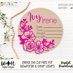 Könnte beinhalten: Eine runde Holzplakette mit einem rosafarbenen Blumendesign und dem Namen "Ivy Irene". Es gibt Felder, um das Datum, die Uhrzeit, das Gewicht und die Länge einzutragen. Die Plakette ist perfekt für eine Babyparty oder ein Kinderzimmer.