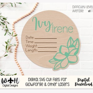 Könnte beinhalten: Ein Holz-Kreis mit hellbraunem Hintergrund und einem grünen Blumenmuster. Der Kreis trägt den Text "Ivy Irene" oben und Platz für "Datum", "Uhrzeit", "Gewicht" und "Länge".