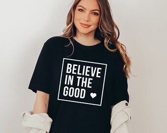May include: A black t-shirt with the text "Believe in the good" in a white box with a small white heart.
