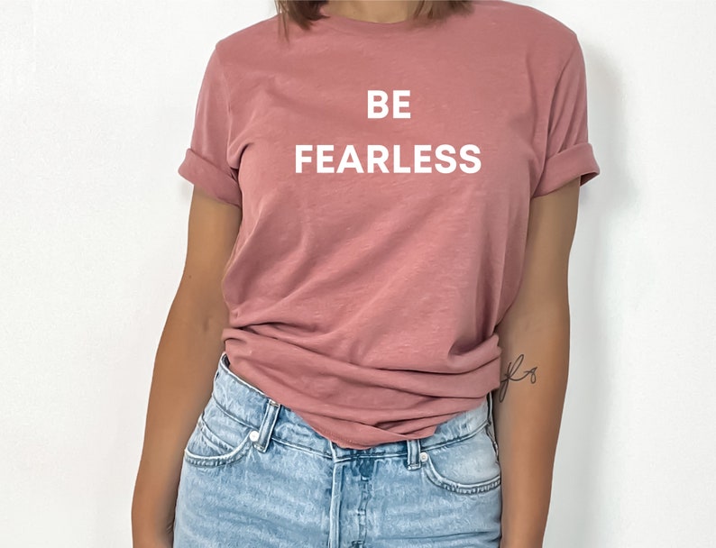 May include: A pink t-shirt with the text "BE FEARLESS" printed in white on the front.