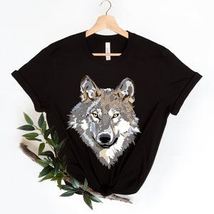 May include: Black t-shirt with a graphic print of a wolf's face. The wolf has gray and brown fur with yellow eyes.