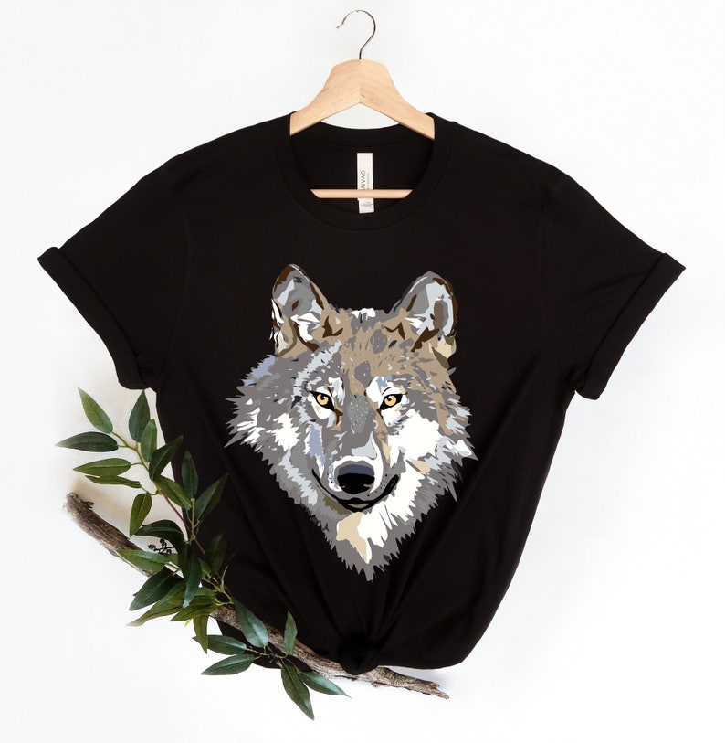 May include: Black t-shirt with a graphic print of a wolf's face. The wolf has gray and brown fur with yellow eyes.
