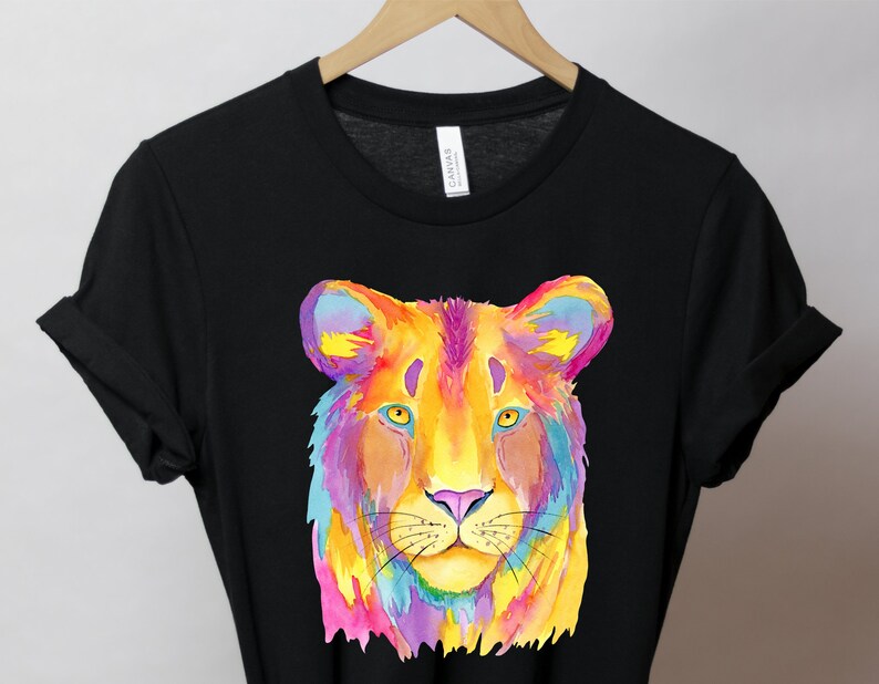 May include: A black t-shirt with a colorful watercolor illustration of a lion's face. The lion's fur is painted in shades of pink, yellow, orange, blue, and purple.
