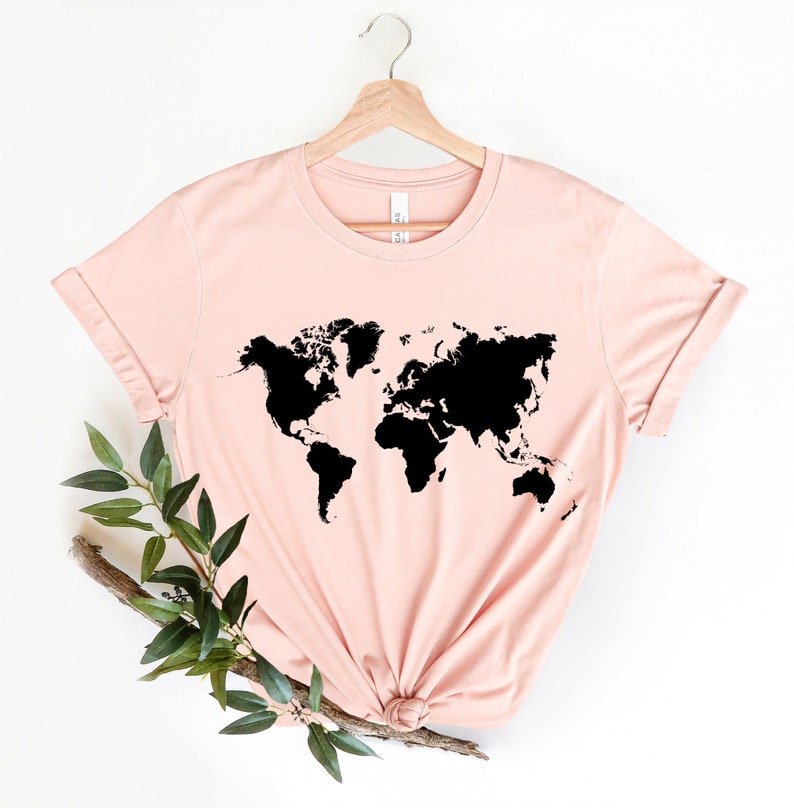 May include: A light pink t-shirt with a black outline of the world map printed on the front.