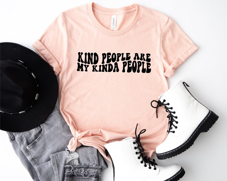 May include: A peach-colored t-shirt with the text "Kind people are my kinda people" in black retro-style lettering.