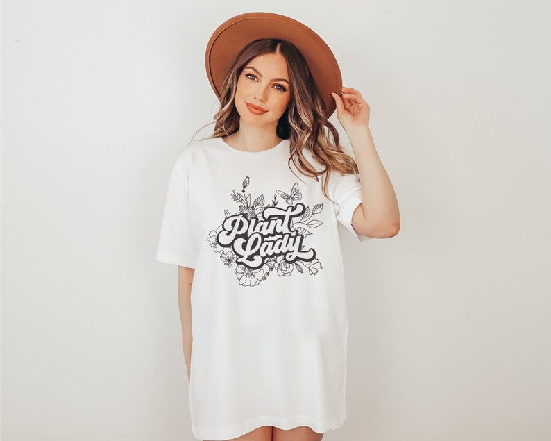 May include: White t-shirt with a black and white graphic design of flowers and the text "Plant Lady" in a retro font.