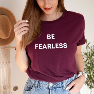 May include: A maroon t-shirt with white text that reads "BE FEARLESS".