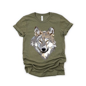 May include: A green t-shirt with a graphic print of a wolf's face. The wolf has gray and brown fur and yellow eyes.