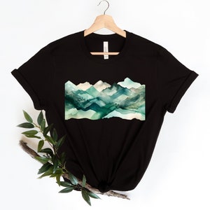 Puede incluir: Camiseta negra con un dise&ntilde;o de acuarela de monta&ntilde;as verdes y azules.