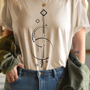 Pode incluir: Uma camiseta branca com um design geom&eacute;trico em preto. O design inclui um c&iacute;rculo, um diamante e uma linha com uma seta na parte inferior.