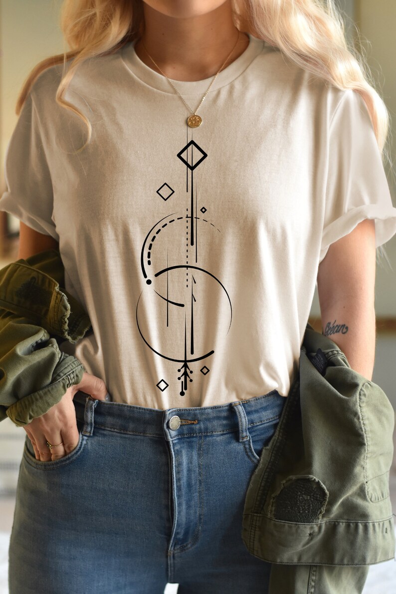 Pode incluir: Uma camiseta branca com um design geom&eacute;trico em preto. O design inclui um c&iacute;rculo, um diamante e uma linha com uma seta na parte inferior.