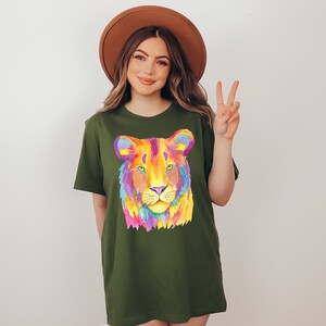 May include: A green t-shirt with a colorful lion face graphic. The lion's face is painted in shades of pink, yellow, blue, and purple.
