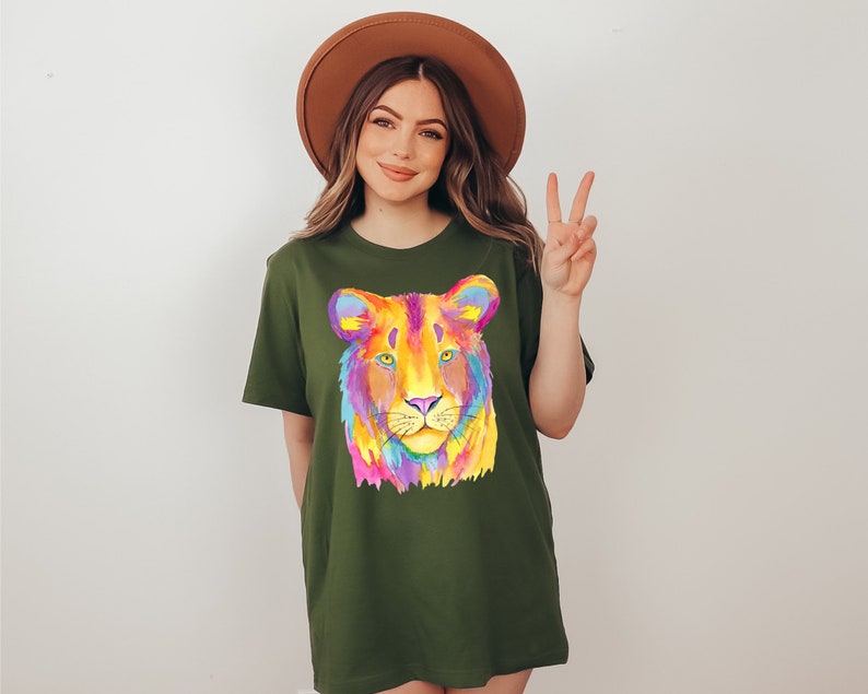 May include: A green t-shirt with a colorful lion face graphic. The lion's face is painted in shades of pink, yellow, blue, and purple.