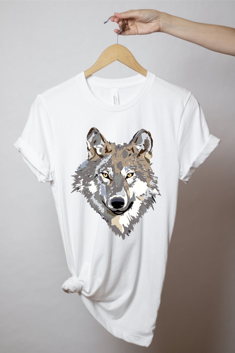 May include: White t-shirt with a graphic print of a wolf's head. The wolf has brown, gray, and white fur with yellow eyes.