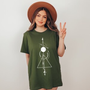 May include: A green t-shirt with a white geometric design featuring a circle, triangle, and arrows. The design is centered on the shirt.