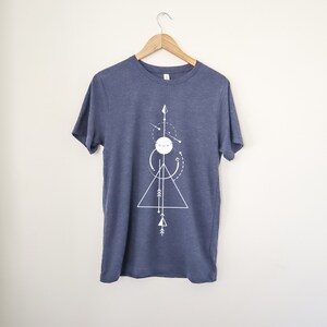 May include: A navy blue t-shirt with a white geometric design featuring a triangle, circle, and arrows.