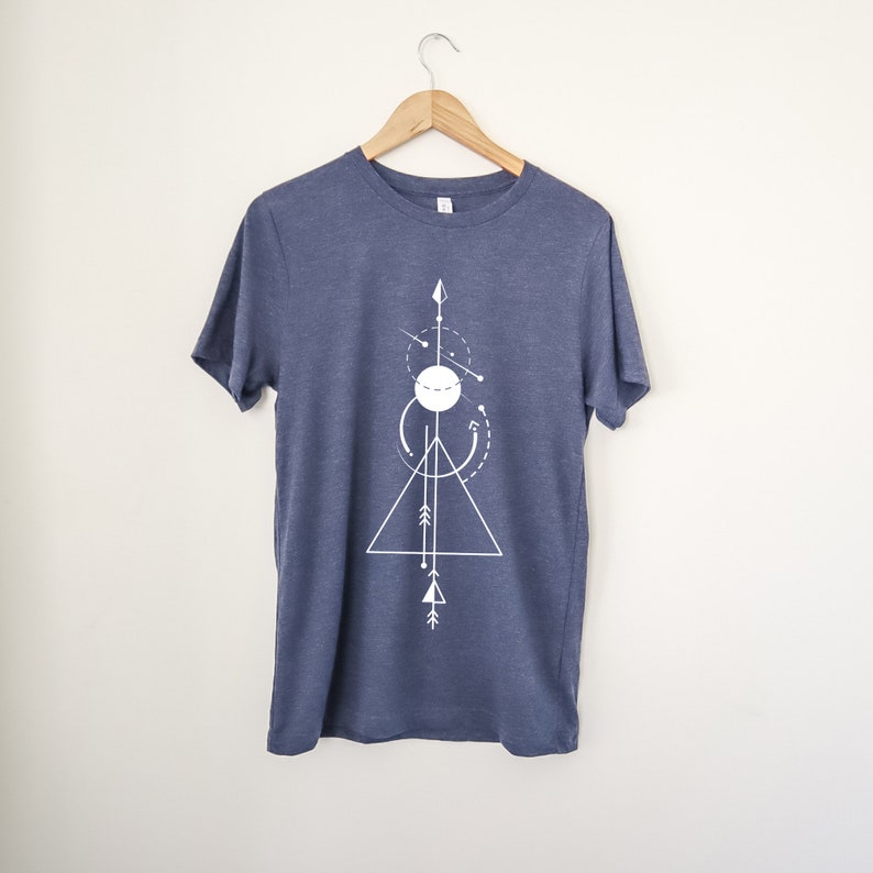 May include: A navy blue t-shirt with a white geometric design featuring a triangle, circle, and arrows.