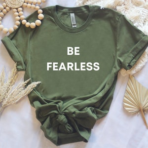 May include: A green t-shirt with the words "BE FEARLESS" printed in white on the front.