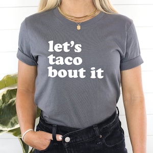 May include: A grey t-shirt with the text "let's taco bout it" in white.