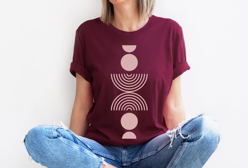 May include: A maroon t-shirt with a pink geometric design featuring circles, half circles, and arcs.