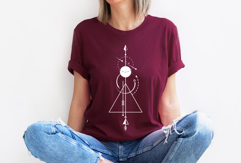 May include: A maroon t-shirt with a white geometric design featuring a triangle, circle, and arrows.