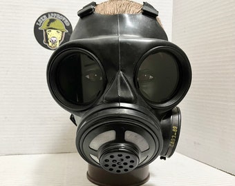 May include: Black gas mask with two large round eye pieces and a black filter on the side. The filter has the text "CA03-89" printed on it.