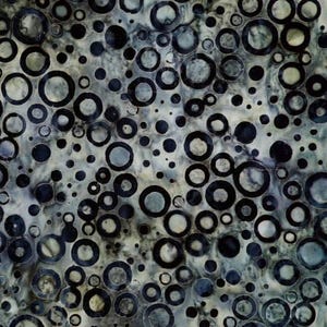 May include: Abstract fabric pattern featuring a repeating design of dark blue and gray circles of varying sizes. The circles are layered over a mottled, light gray and blue background, creating a textured appearance. The design is suitable for various textile applications.