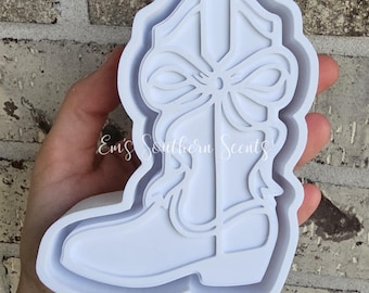 May include: A white, cowboy boot-shaped mold with a bow detail. The mold is made of a flexible material and is designed for crafting. The text "Ems Southern Scents" is visible on the mold.