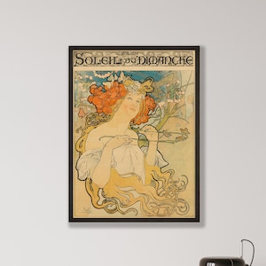 May include: Framed art print featuring a woman with flowing blonde hair and a floral headdress, holding a branch. The artwork has a vintage style with the text "SOLEIL DU DIMANCHE" at the top. The print is in a black frame.
