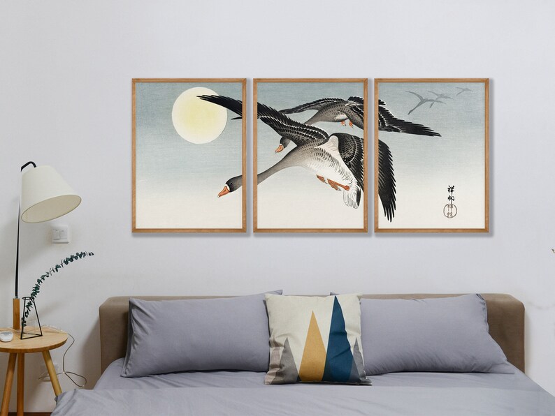 May include: A triptych of framed art prints featuring a flock of geese in flight against a pale blue sky and a full moon. The artwork has a traditional Japanese aesthetic, with muted colors and a minimalist style.